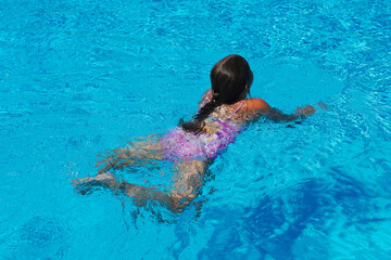 Little girl at swimming pool. Smiling Girl having fun in swimming pool on summer vacation. Swimming girl.