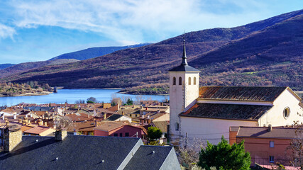 Old church with bell tower in an old village in the green valley of high mountains. Lozoya Spain.