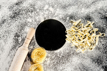 Freshly cooked pasta is lying on a dark surface dusted with flour. Italian pasta. Tagliatelle. Raw pasta. Italian pasta recipe. Top view, copy space