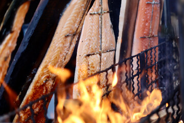 Flames of fire roasting filet pieces of salmon in the background. Christmas market in Luxembourg