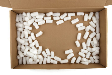 Styrofoam packing peanuts in cardboard box isolated in on white background. White plastic foam...