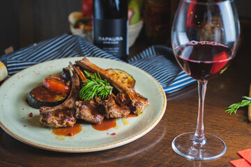 Fried ribs with a glass of red wine on a table in a restaurant close-up