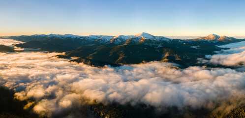 Plakat Aerial view of vibrant sunrise over white dense fog with distant dark Carpathian mountains on horizon