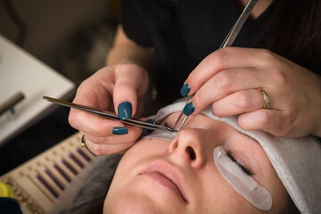 Eyelash extensions. A girl in a cosmetology salon.