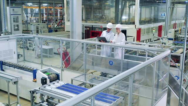 Solar cells manufacturing is being observed by two employees