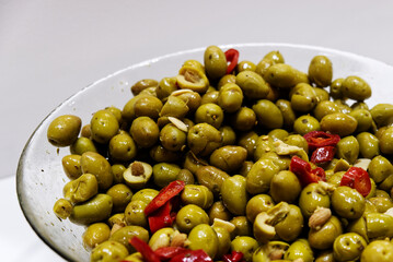 a glass bowl with crushed green olives seasoned with oil and chilli pepper