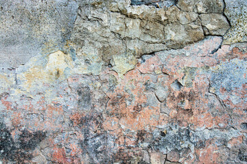 Old cracked weathered painted wall background texture. Light peeled plaster wall with falling off flakes of paint