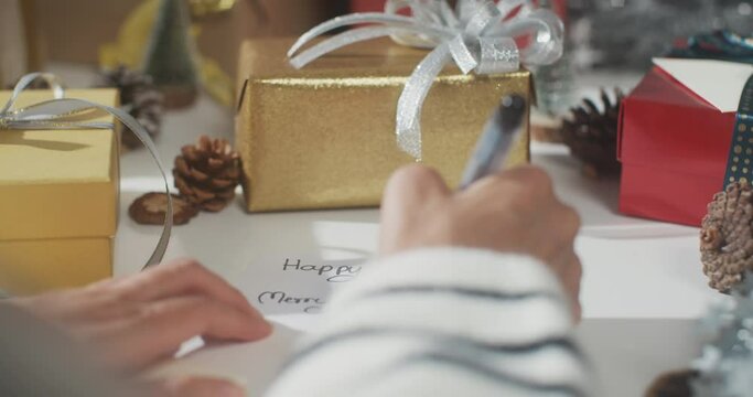 Close up of girl hands writing greeting card winter christmas decorations on table. Minimal creative flat lay of christmas traditional composition and new year holiday season.