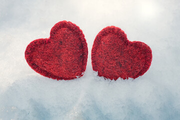 Obraz premium two red woolen hearts on the snow in winter, Valentine's Day decoration, 14 February background