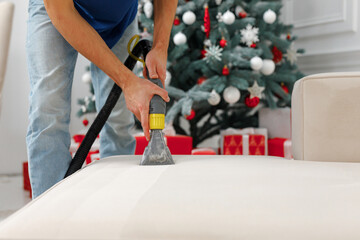A man vacuuming a sofa in a christmas decorated room