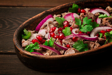 Traditional Georgian cuisine, Kuchmachi, chicken giblets, in ketsi, on a wooden table, close-up, horizontal, no people,