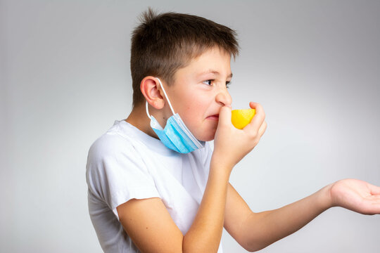 Anosmia Or Smell Blindness, Loss Of The Ability To Smell, One Of The Possible Symptoms Of Covid-19, Infectious Disease Caused By Corona Virus. Boy Trying To Sense Smell Of A Lemon