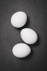 three chicken eggs on a textured surface - black and white photo