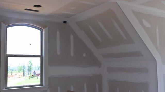 Finishing plastering drywall in ready for paint with new house under construction