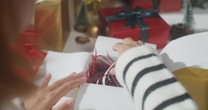 Close up of girl hands wrapping present gift box winter christmas decorations on table. Minimal creative of christmas traditional composition and new year holiday season.