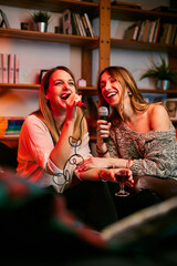 Talented girls with beautiful voices sit at home and sing a duet at karaoke night. - 474951792