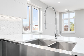 Fototapeta na wymiar A stainless steel apron sink with a marble counter top, chrome faucet, and a view towards an empty living room.