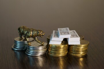 A metal tiger with a wad of dollars on the table in close-up.