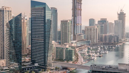 Fototapeta premium Aerial view to Dubai marina skyscrapers around canal with floating boats timelapse