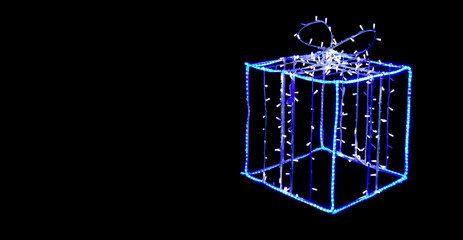 Outline of a gift box on a black background. Light illumination.copyspace for text.