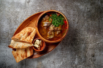 Beef goulage with garlic and pita bread and cutlery on a gray stone table