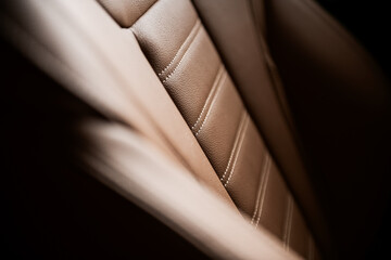 Luxury car interior. Detail view of a leather covered front seat, brown color, inside a premium...
