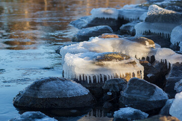 Fototapeta premium Winter landscape with ice and stones on frozen Sea. Ice frozen on a stone. Sea shore in winter, covered with ice and snow