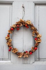 Scandinavian style Christmas wreath made of dried plants and berries hanging on the grey door during Christmas and New Years holidays in Sweden. 