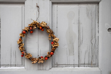 Scandinavian style Christmas wreath made of dried plants and berries hanging on the grey door during Christmas and New Years holidays in Sweden. 