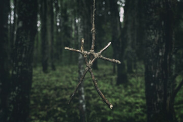 Sticks symbol. Magic occult symbol. Black magic. Totem hanging on tree in dark forest. Witchcraft...