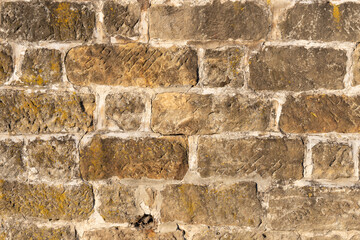 Stone block wall background. Weathered building exterior surface as an abstract texture. Natural dirty facade backdrop.
