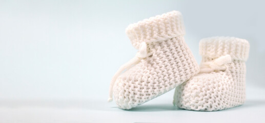 Crochet white baby booties, on a gray background, handmade baby booties, warm baby feet is a...