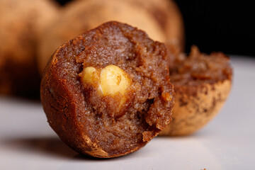 Beautiful candy truffle with a nut inside on a white plate on a black background