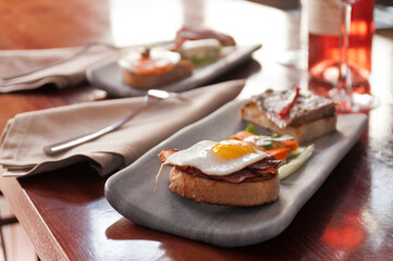 Tapas en plato de mármol en restaurante con vino rosado.