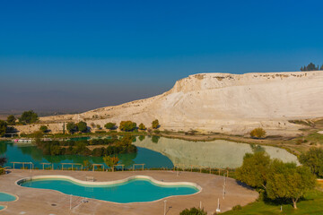 Fototapeta na wymiar PAMUKKALE, TURKEY: Landscape with a view of a pond in a Natural Park and white travertine on a sunny day in Pamukkale.