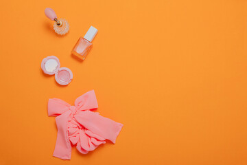 Makeup products,  cosmetics and scrunchie on orange background. Flat lay, top view. Beauty blog banner template.
