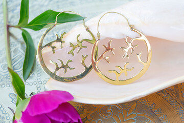 Brass metal earring on natural neutral background