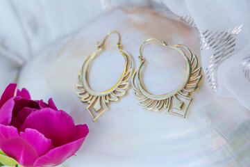 Brass metal earring on natural neutral background