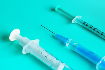 Hypodermic syringe and needles on cyan table, closeup detail