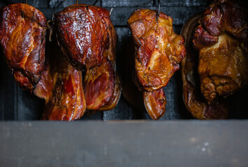 Close up of smoked meat and belly or beech meat with dark crust in the smokehouse or smoker, food concept