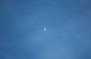 Moon in the clouds, blue sky.