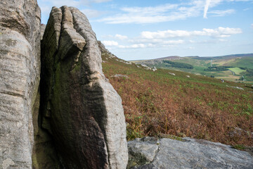 A giant rock halved by erosion sits on a hill overlooking moorland, Peak District, UK
