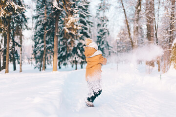 The boy throws snow with a shovel in winter lifestyle . Winter walks. An article about children's winter leisure.