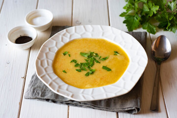 Family lunch: Mashed pea soup with fresh herbs in a white plate on a white background. Close-up.
