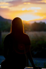 Silhouette of young teen girl sitting on the bench