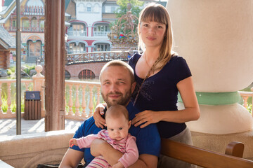 Happy beautiful family of three with one year old child posing for photographer in restaurant
