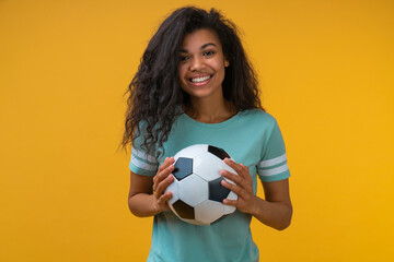 Studio shot of attractive confident smiling soccer player girl posing with a ball in hands