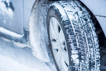 Closeup view of winter tires on a road covered with snow in cold freeze winter months.