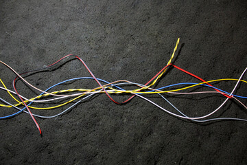 Wires of different colors on a gray background. A bunch of multicolored wires on a dark background top view.  Intertwined wires among themselves. Cable for connection.