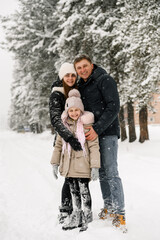 Fototapeta na wymiar Happy family have fun in winter forest. Mother, father and dauther playing with snow.Enjoying spending time together. Family concept